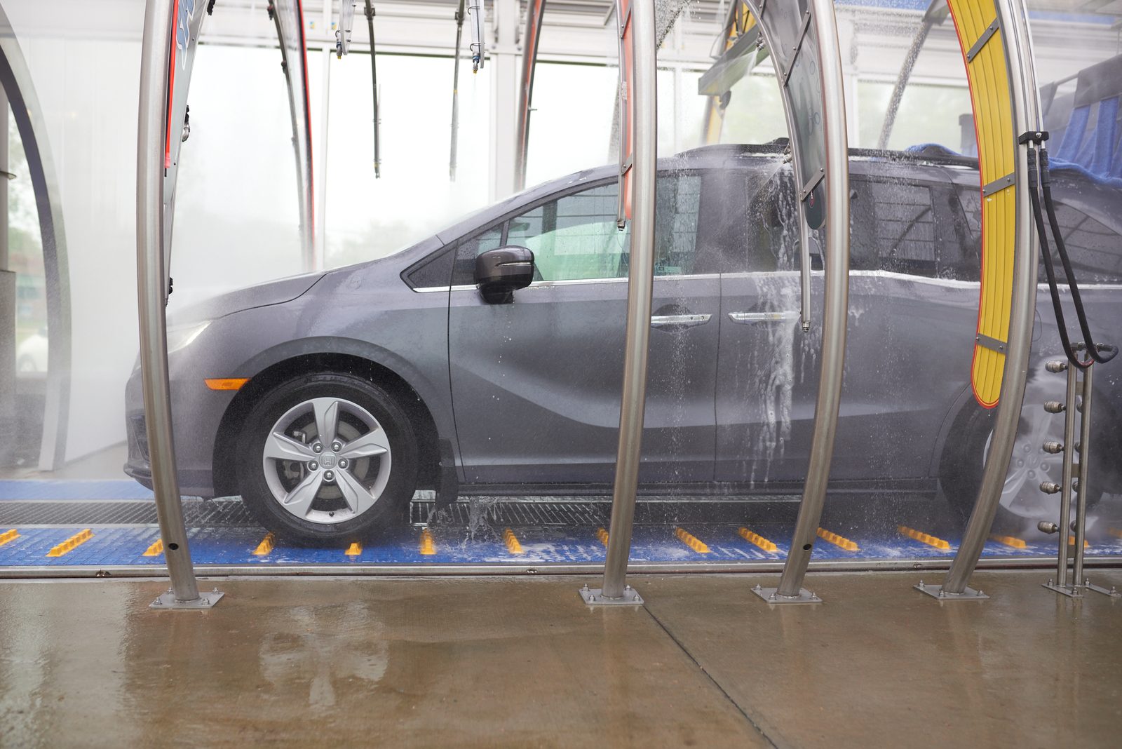 A car moving through a Brite WorX wash tunnel, water running down its side