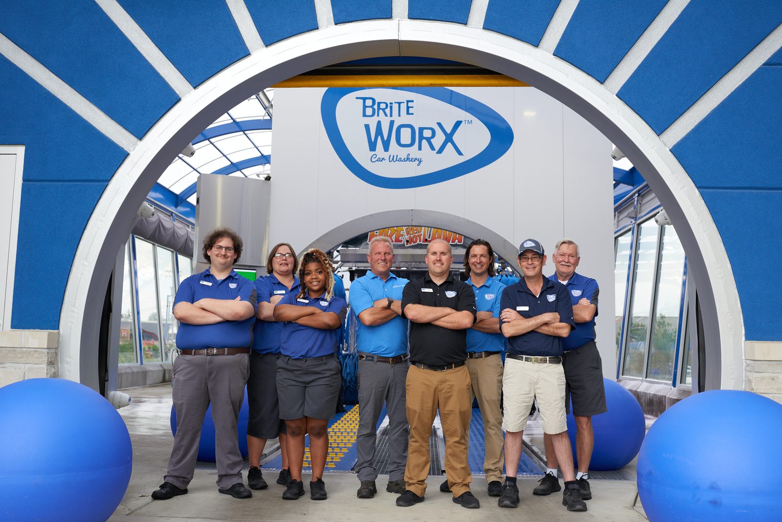 The Brite WorX team standing together under the blue wash arch outside one of the stores