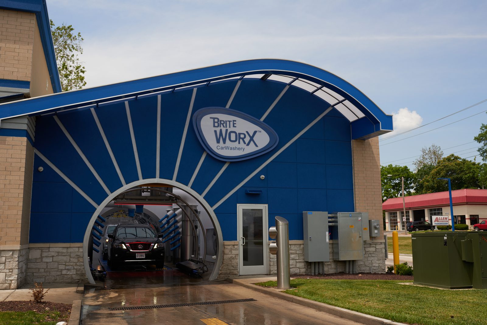 The entrance to a Brite WorX tunnel, a car on the conveyor under the arch and the sunburst of the blue building above it
