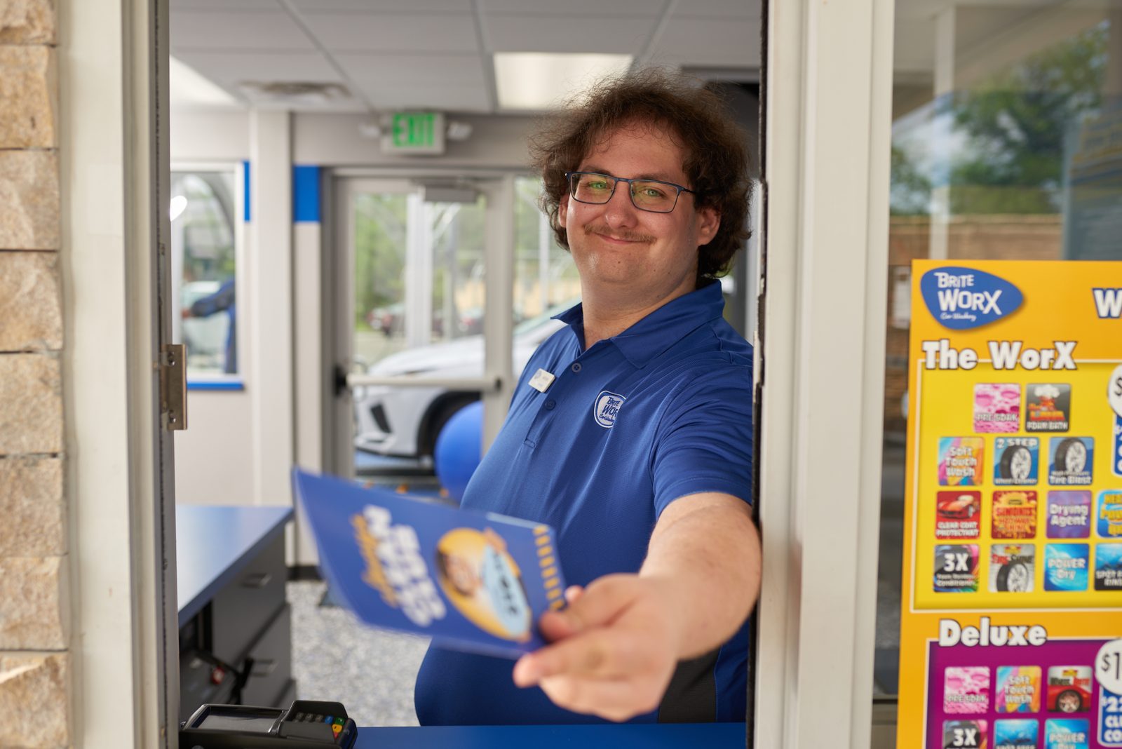 A Brite WorX team member leaning out of the pay window to hand over an Always Clean Club card